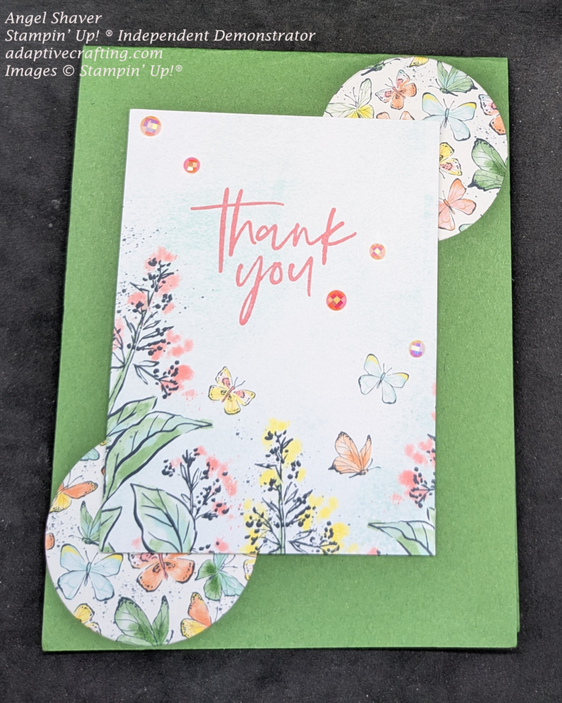 Green card with two circles at top right and bottom left with multiple butterflies on them.  Center rectangle is placed on top of both circles and has printed flowers and flying butterflies.  The sentiment "Thank You" is stamped toward the top and it is decorated with pearlized faceted circles.