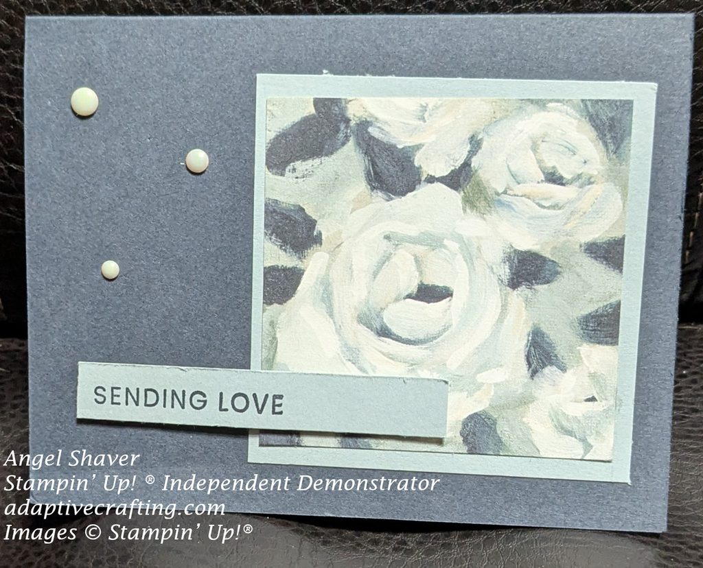 Blue card with patterned paper of white roses framed in lighter blue card.  Strip of lighter blue paper has sentiment that says,  "sending love."  Antique pearls complete card.
