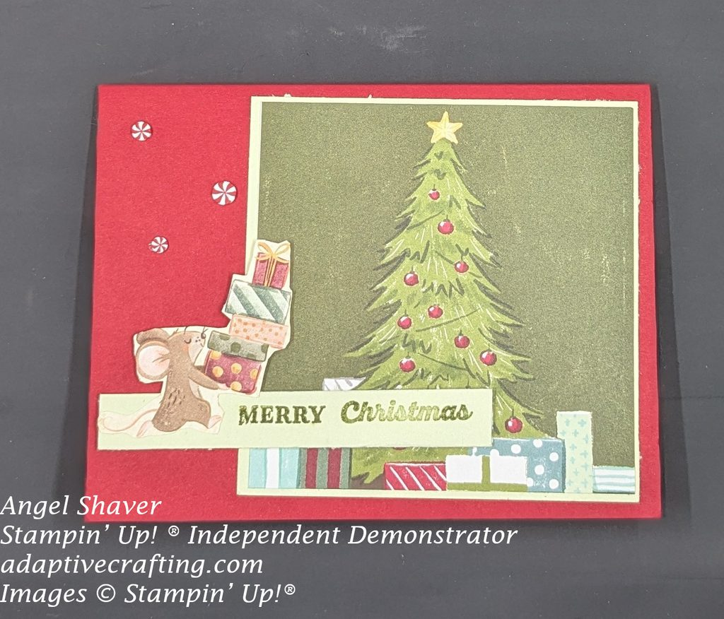 Red card with patterned paper of Christmas tree and presents framed with white paper.  Sentiment strip says Merry Christmas.  Mouse carrying gifts is on the sentiment strip.  Card is decorated with peppermint embellishments.
