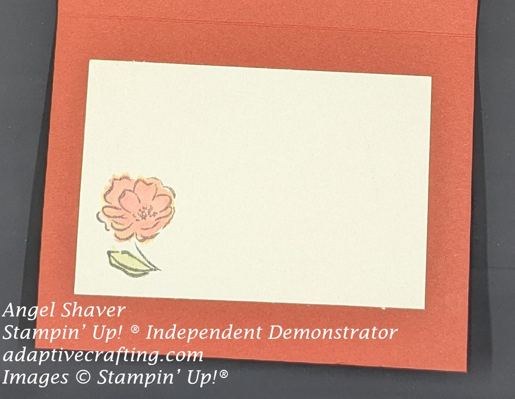 Rust colored card with cream rectangle on card interior with small stamped flower watercolored with same rust colored petals and green leaves.